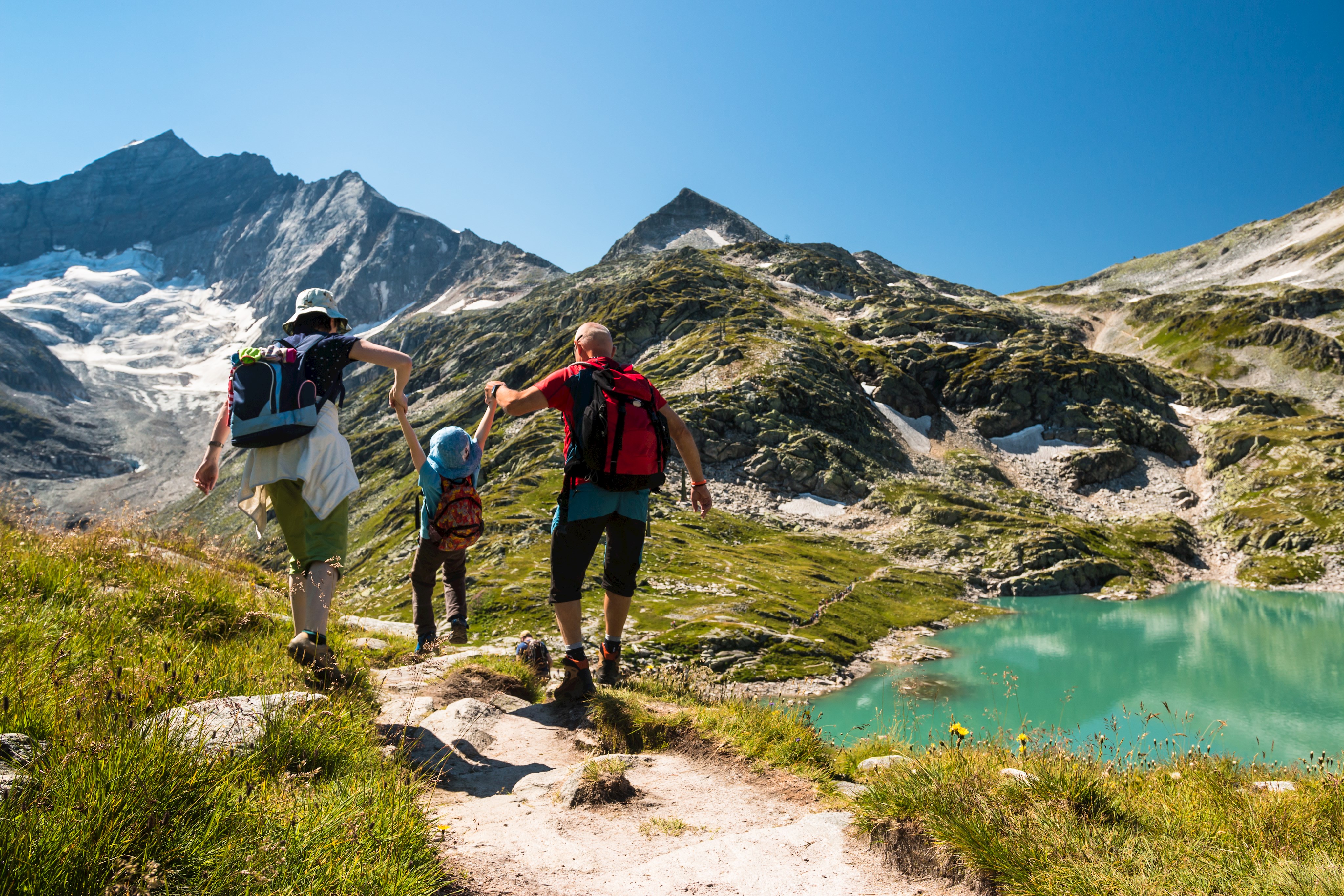 Familie an blauem Bergsee bei schönem Wetter