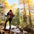 Ein Wanderer mit Gepäck und Stöcken im sonnigen, verschneiten Wald