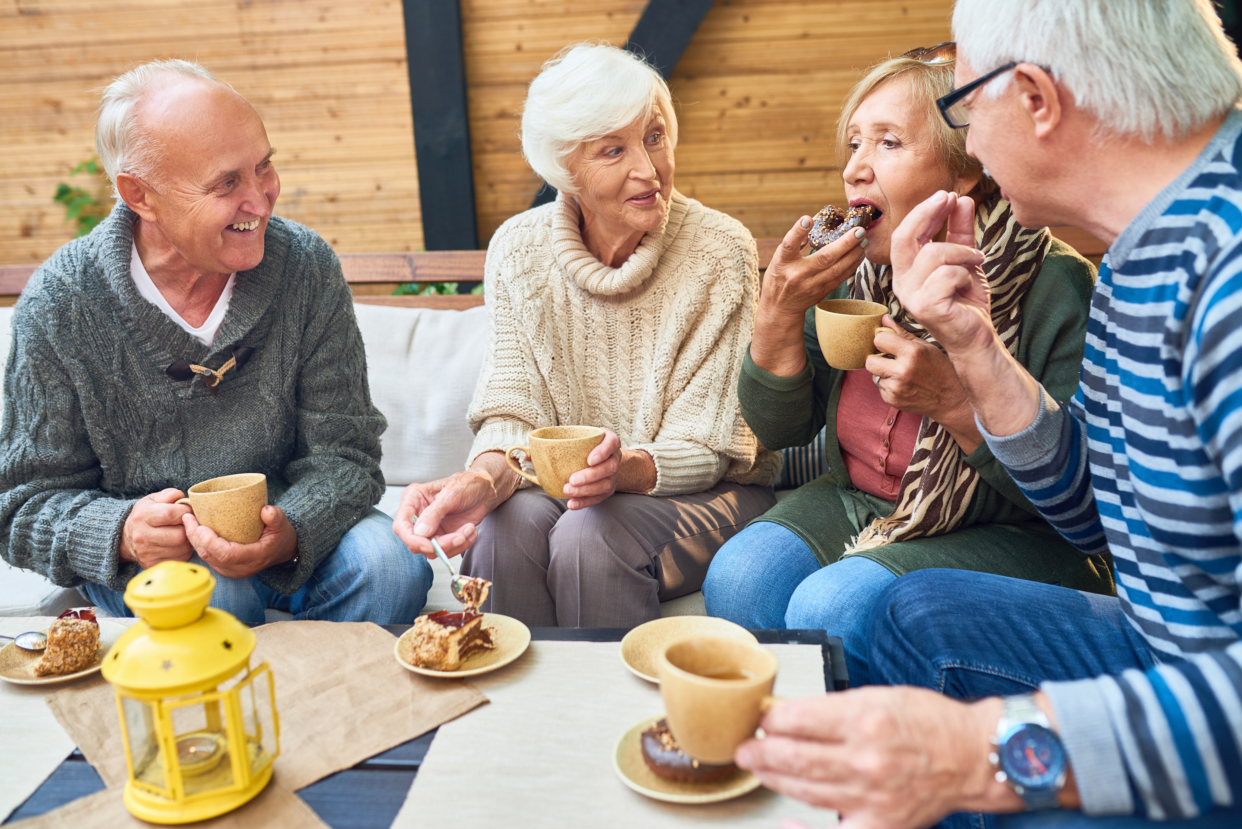 Senioren sitzen an Tisch mit Kaffee und Kuchen