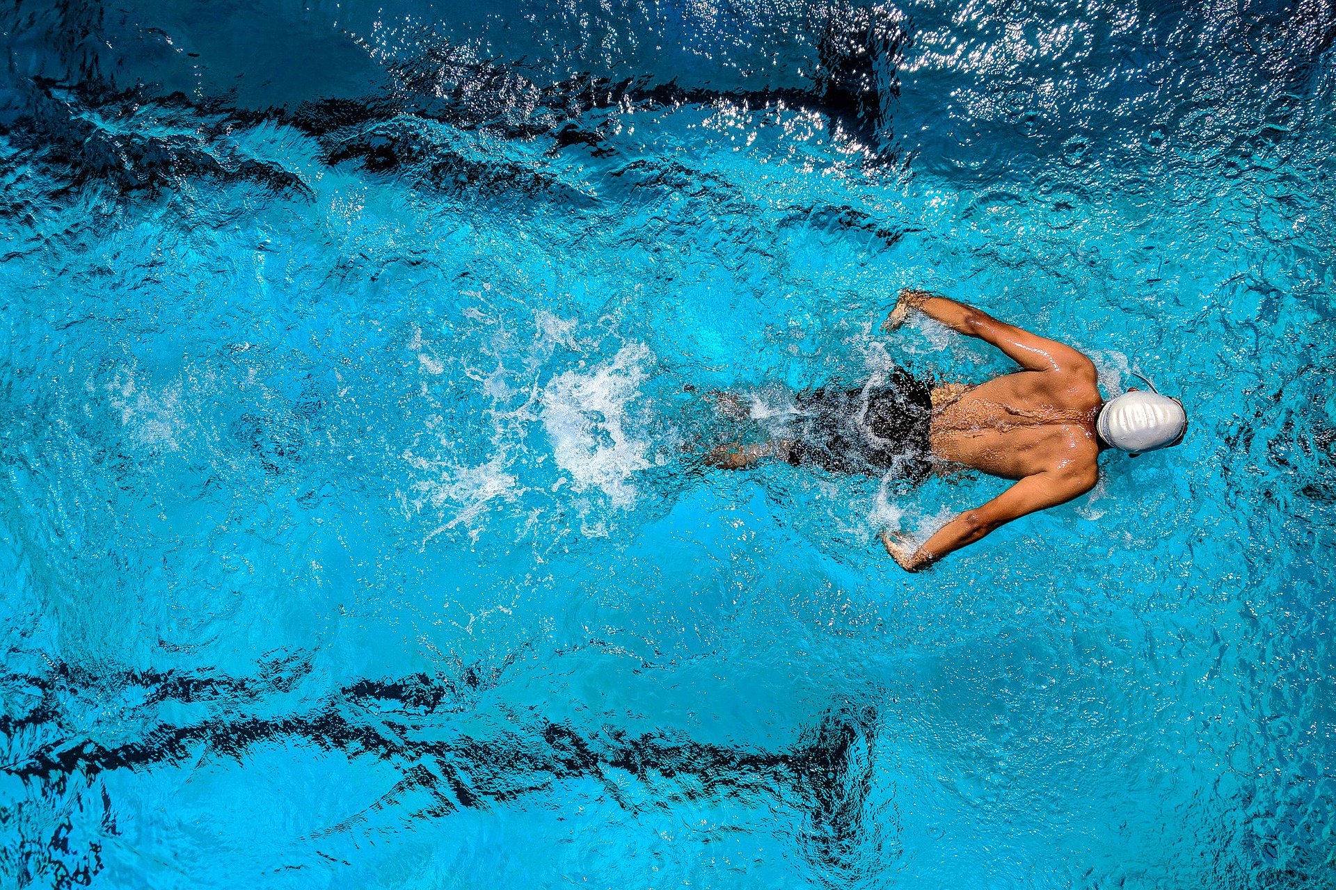 Schwimmender Mann mit Badekappe im Wasser