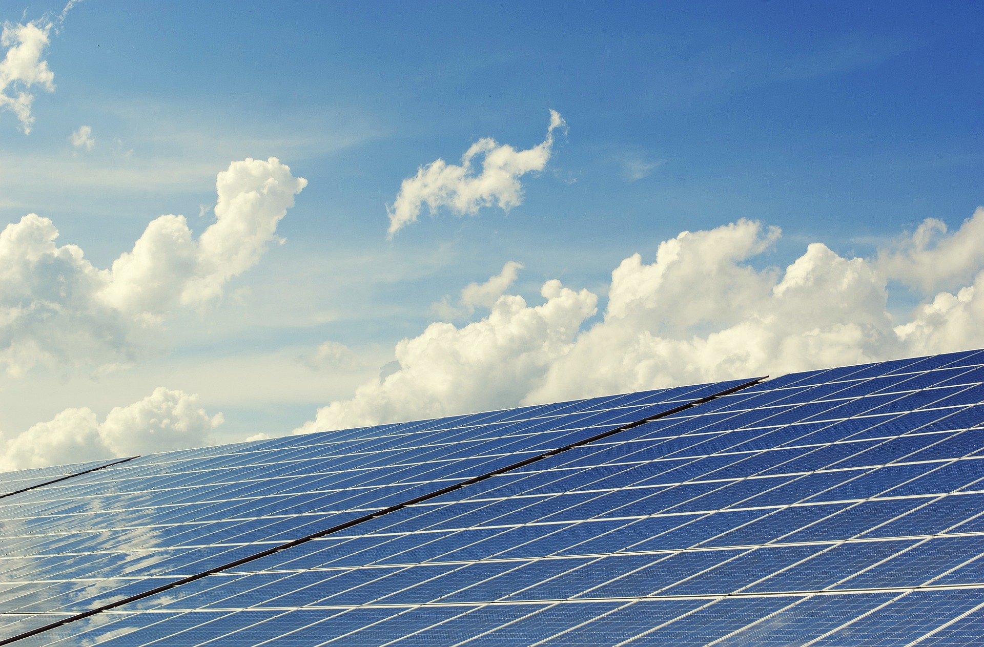 Solarpanels vor blauem, mit Wolken überzogenem Himmel