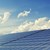 Solarpanels vor blauem, mit Wolken überzogenem Himmel